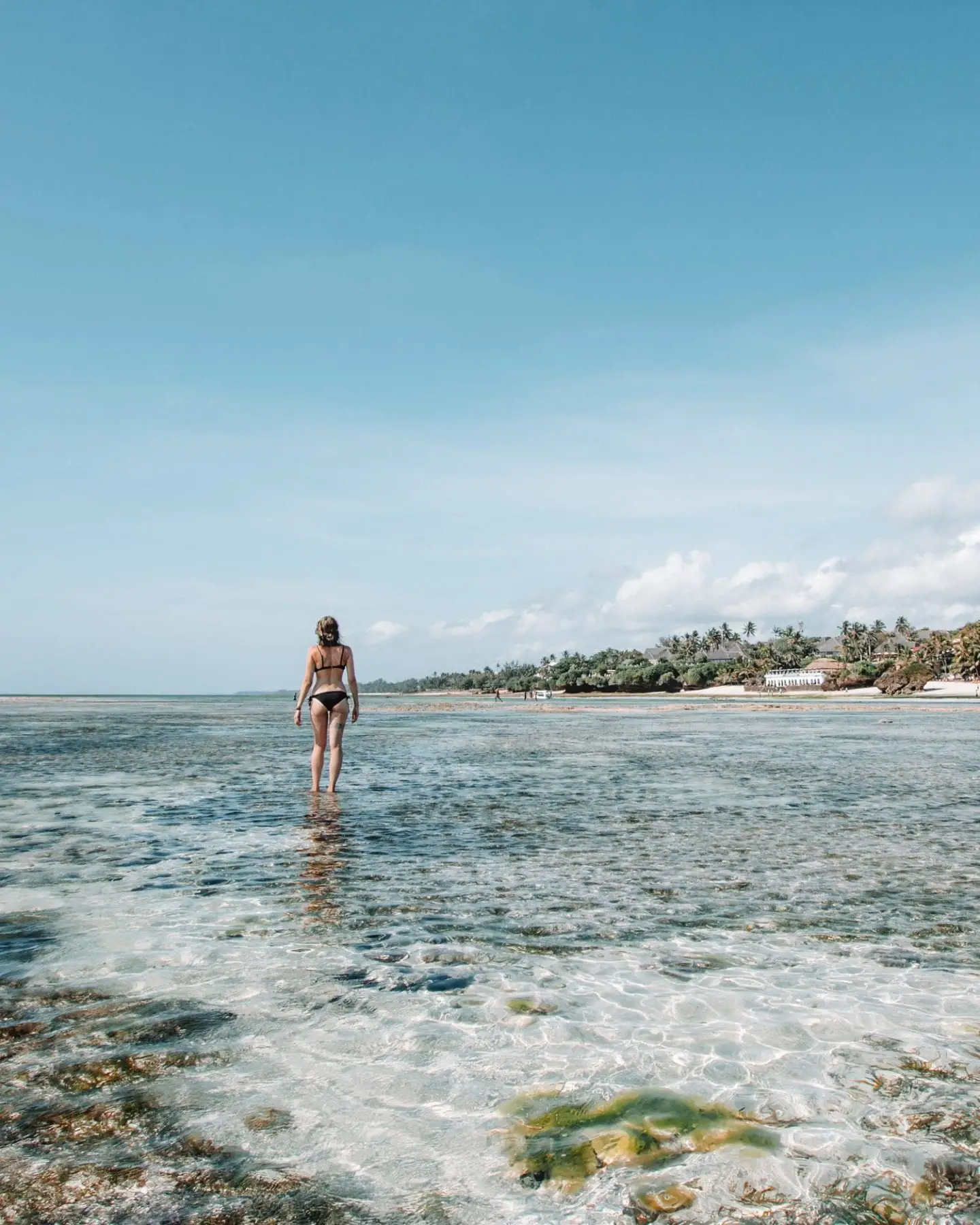 girl walking in the ocean at diani beach, kenya
