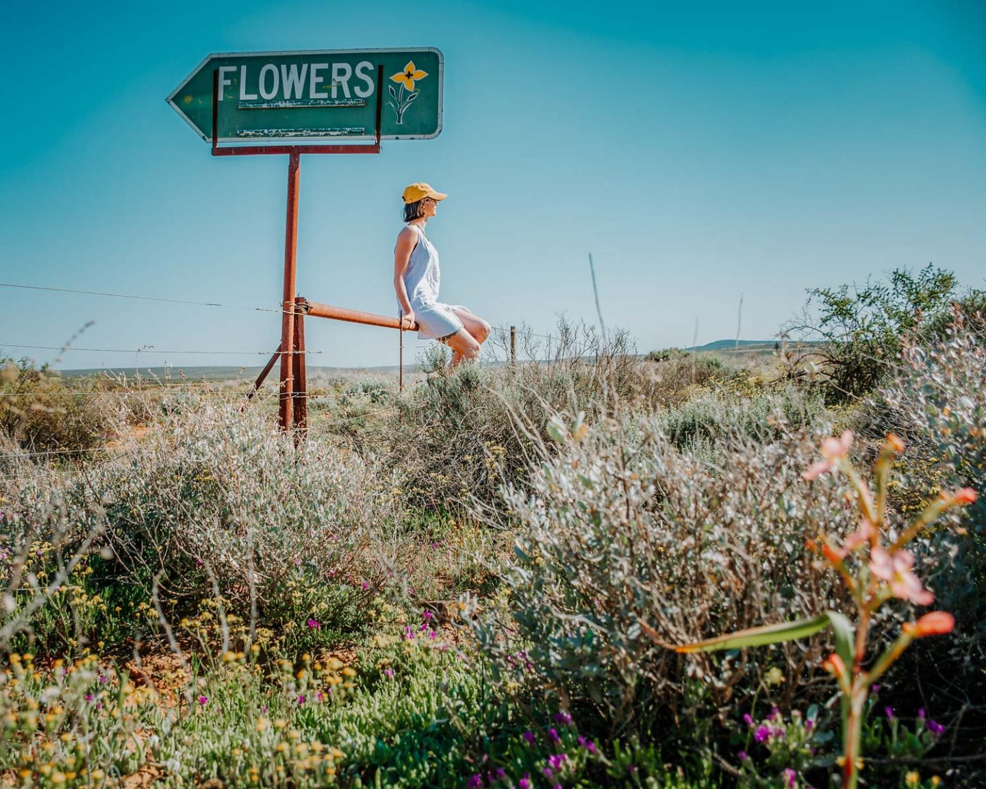 girl sitting next to flower sign