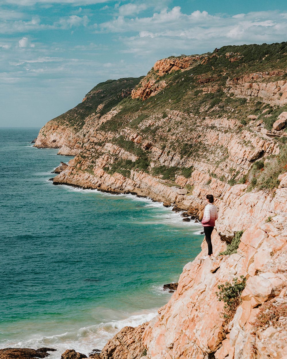 girl standing on the edge of a cliff in robberg nature reserve