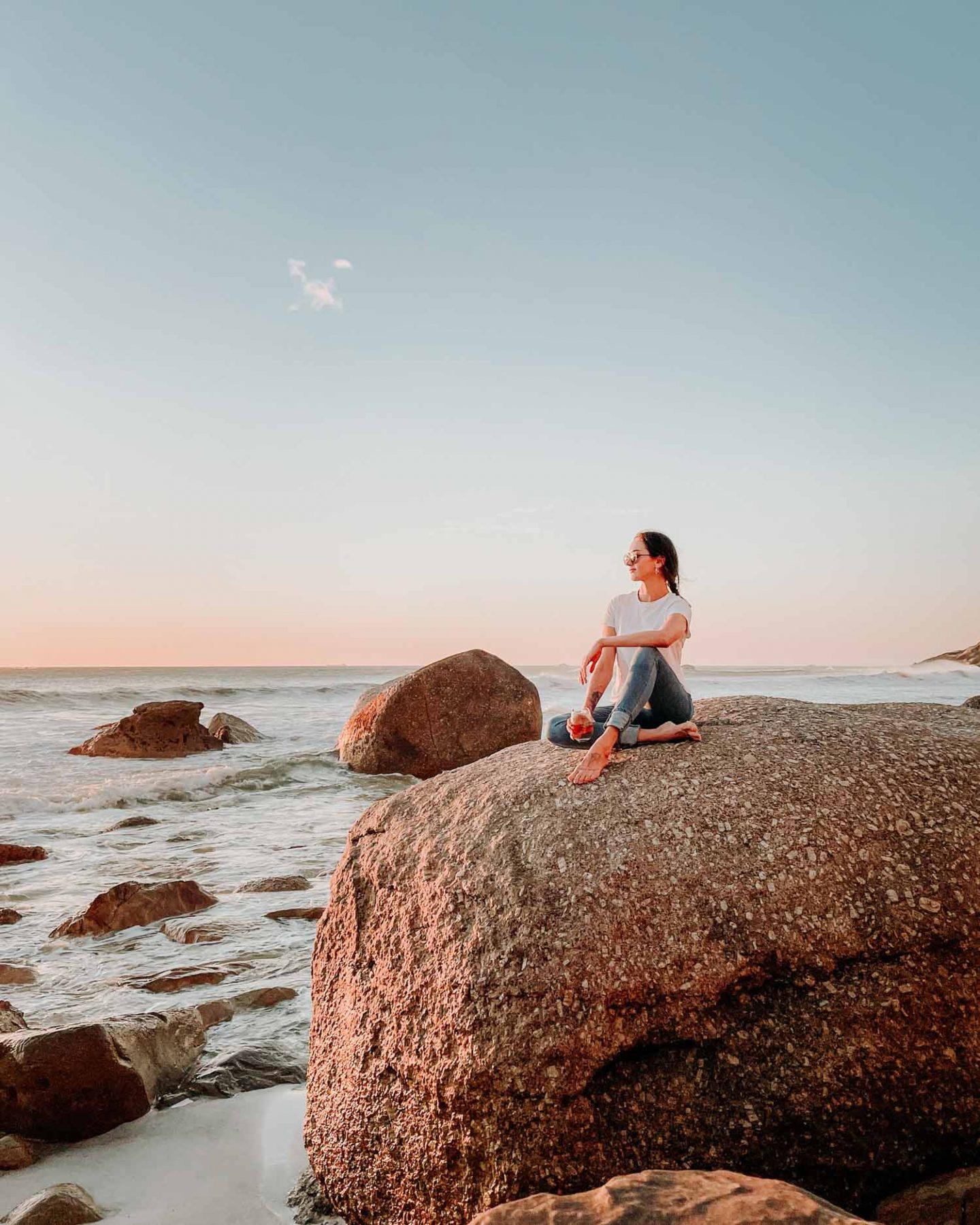 lauren sitting on a rock at sunset on clifton 4th beach