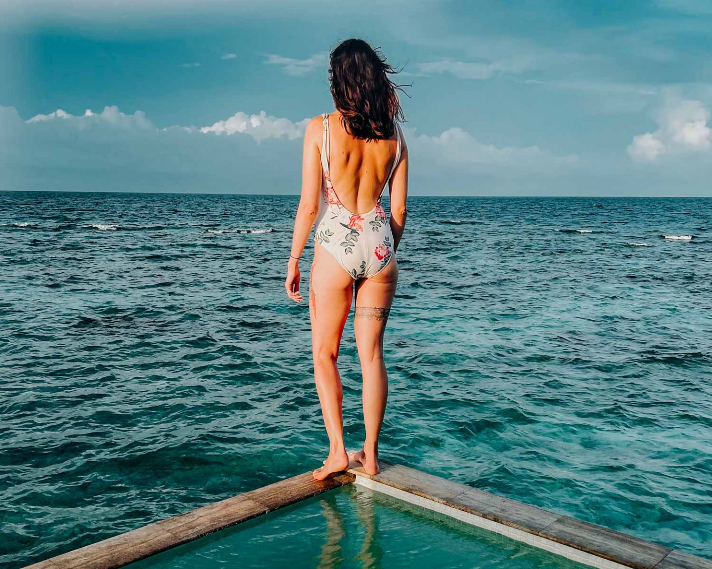 girl standing on the edge of a pool in the maldives